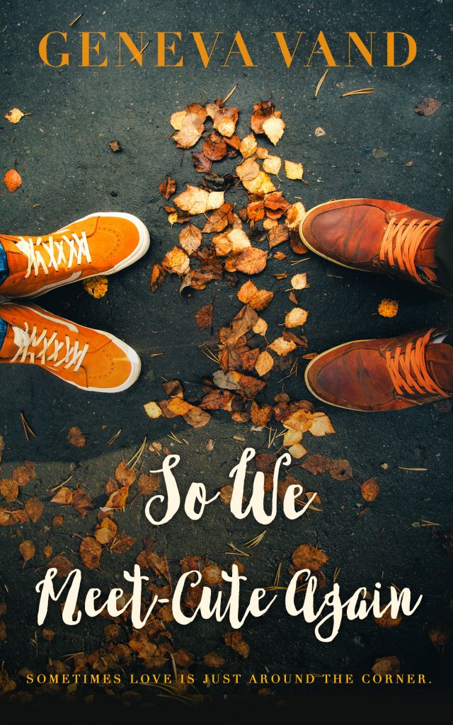 Cover image for So We Meet-Cute Again by Geneva Vand. The image shows the feet of two people facing each other, standing on a leaf-strewn sidewalk.